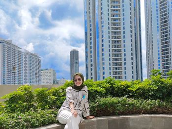 Portrait of young woman against modern buildings in city