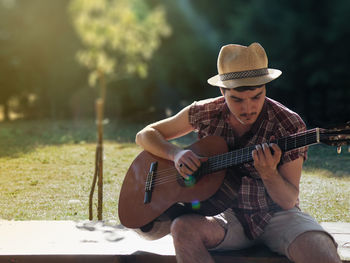 Young man playing guitar on grass