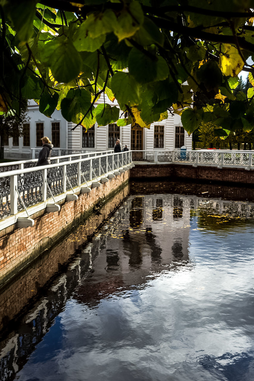 BRIDGE OVER CANAL AMIDST BUILDINGS IN CITY