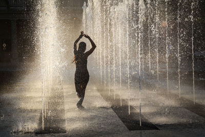 Woman dancing amidst fountain