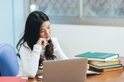 Young woman using mobile phone while sitting on table