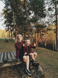 Full length of mother and son blowing bubble sitting outdoors