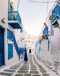 Rear view of woman on alley amidst buildings against sky