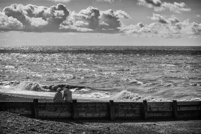 People looking at sea against sky