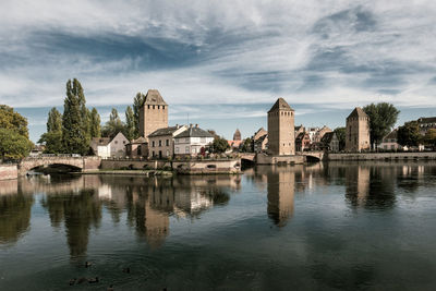 Buildings by river against sky in city