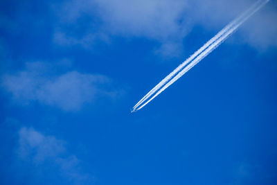 Low angle view of airplane flying against blue sky