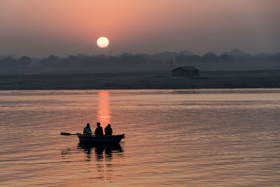 People in boat on sea during sunset