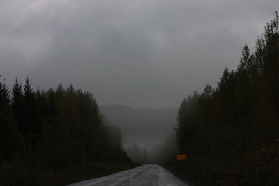 Road amidst trees in forest against sky