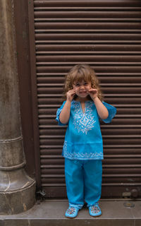 Portrait of girl standing against wall