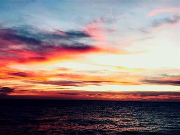 Scenic view of sea against dramatic sky during sunset
