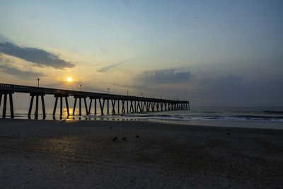 Pier over sea against sky during sunset