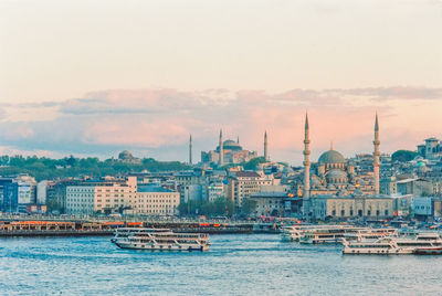 Boats in river with city in background