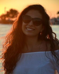 Portrait of young woman wearing sunglasses at sunset