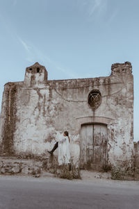 Side view of teenage girl standing against old ruin