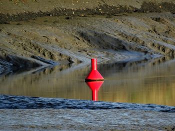 Red water on rock by lake against mountain