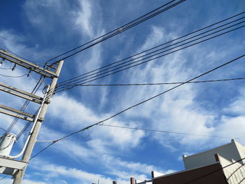 Low angle view of electricity pylon against cloudy sky