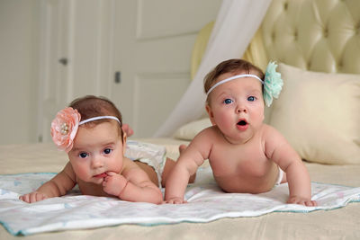 Girls twins in diapers lie on the bed on his stomach