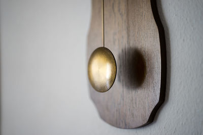 Close-up of antique metallic pendulum against wall