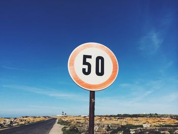 Road sign against blue sky