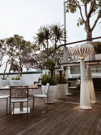 Chairs and table by swimming pool against trees