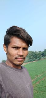 Portrait of young man standing on land against clear sky