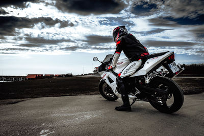 Man riding motorcycle on road against sky