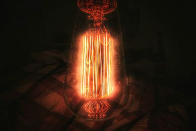 Close-up of illuminated light bulb against black background