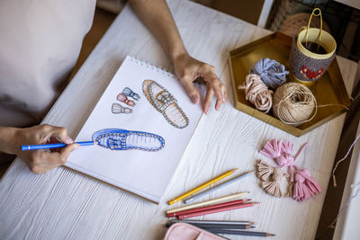 High angle view of woman designing shoes on paper at home