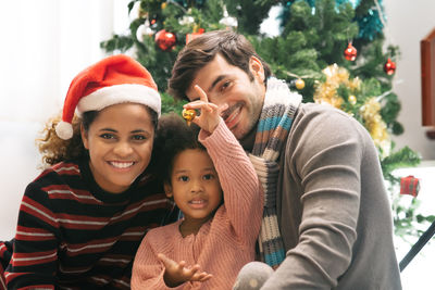 Portrait of smiling family against christmas tree