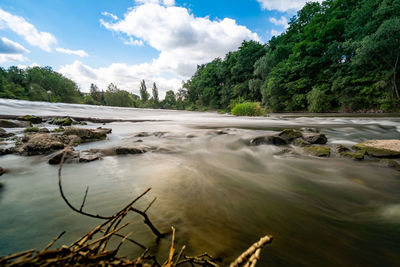 Scenic view of river flowing in forest against sky