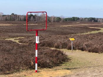 Road sign on field against sky