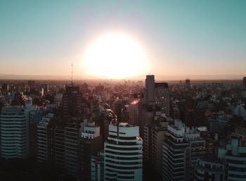 Aerial view of modern buildings in city against sky during sunset
