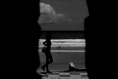 Silhouette woman standing by sea against sky