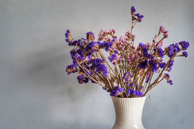 Close-up of purple flower vase on table against wall