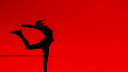 Stretching woman against red background