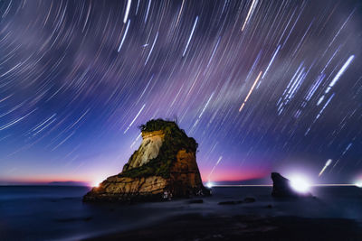 Firework display over sea against sky at night