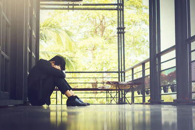 Side view of depressed young man sitting on porch
