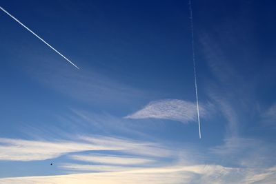 Low angle view of vapor trails against blue sky