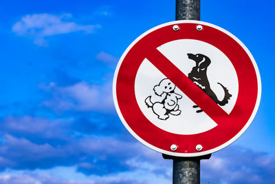 Low angle view of road sign against blue sky