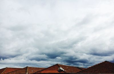 Rooftops of houses against cloudy sky