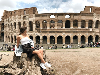 Woman sitting on historical building