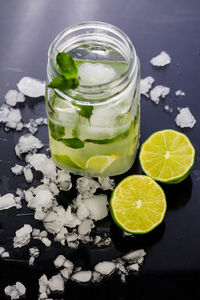 High angle view of mojito in glass jar by lime and ice on table