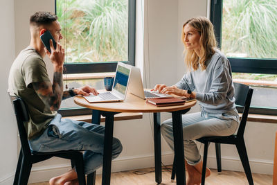 A young married couple use laptops while working in the apartment.