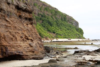 Scenic view of sea by cliff against sky