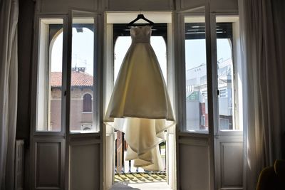 Wedding dress hanging against window at home