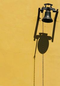 Low angle view of electric lamp against yellow wall