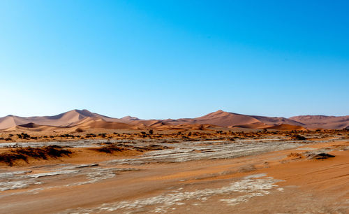 Scenic view of desert against clear blue sky