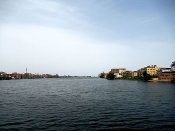 River by buildings in town against sky
