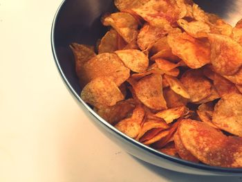 Close-up of potato chips in bowl on white background