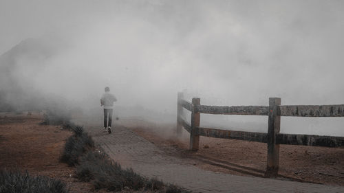 Rear view of man walking on foggy day